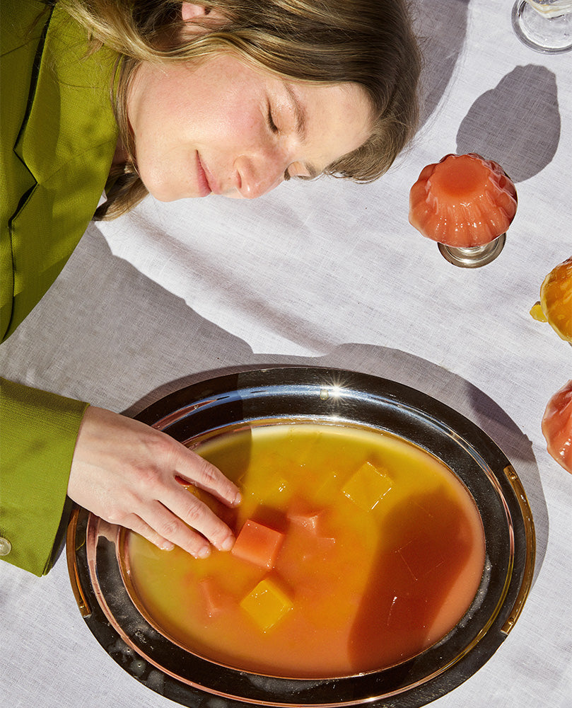 Gelée founder Zoe on white linen blanket with tray of jelly cubes