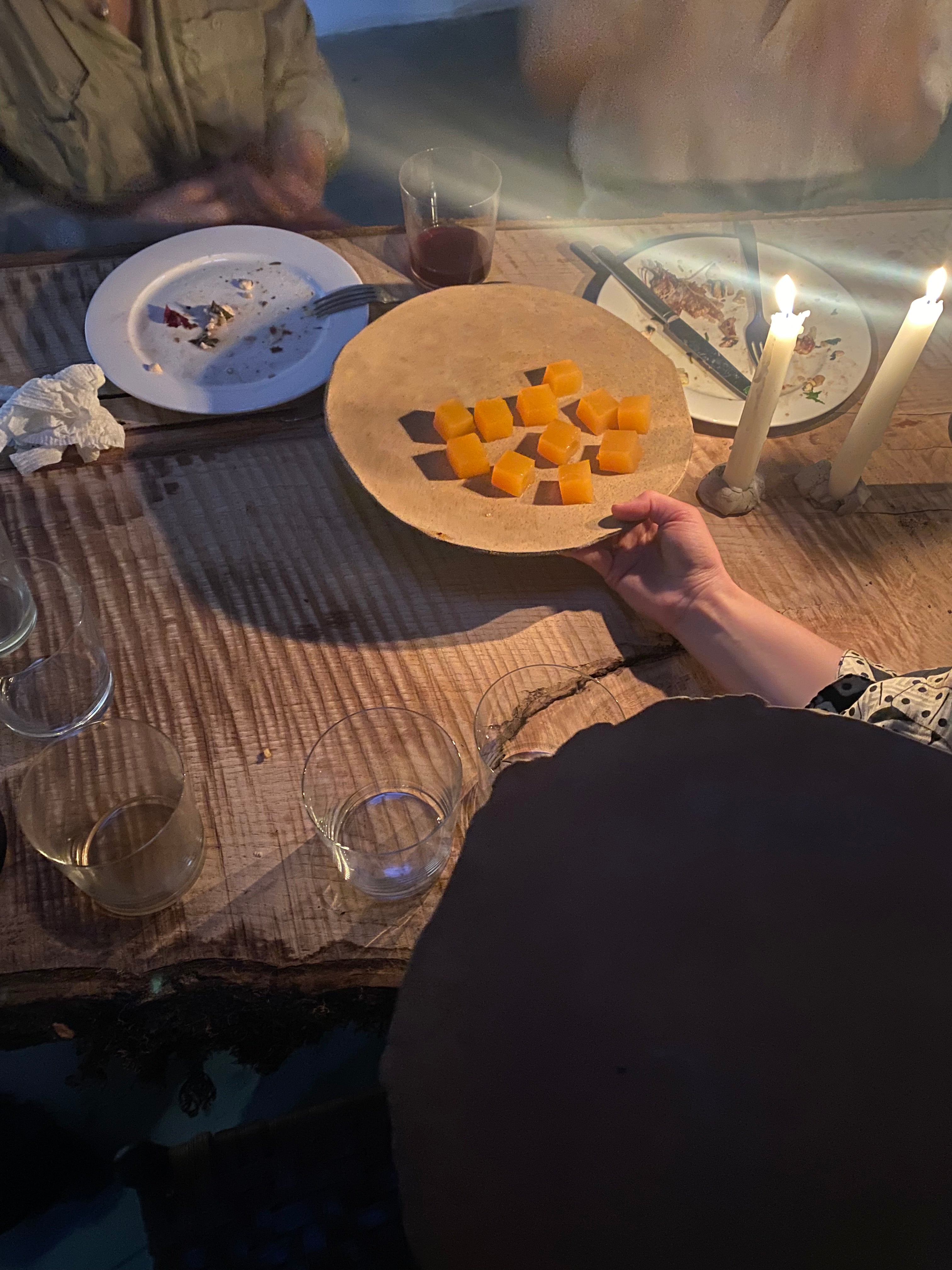 People at a table with a plate of jelly cubes and candlelight