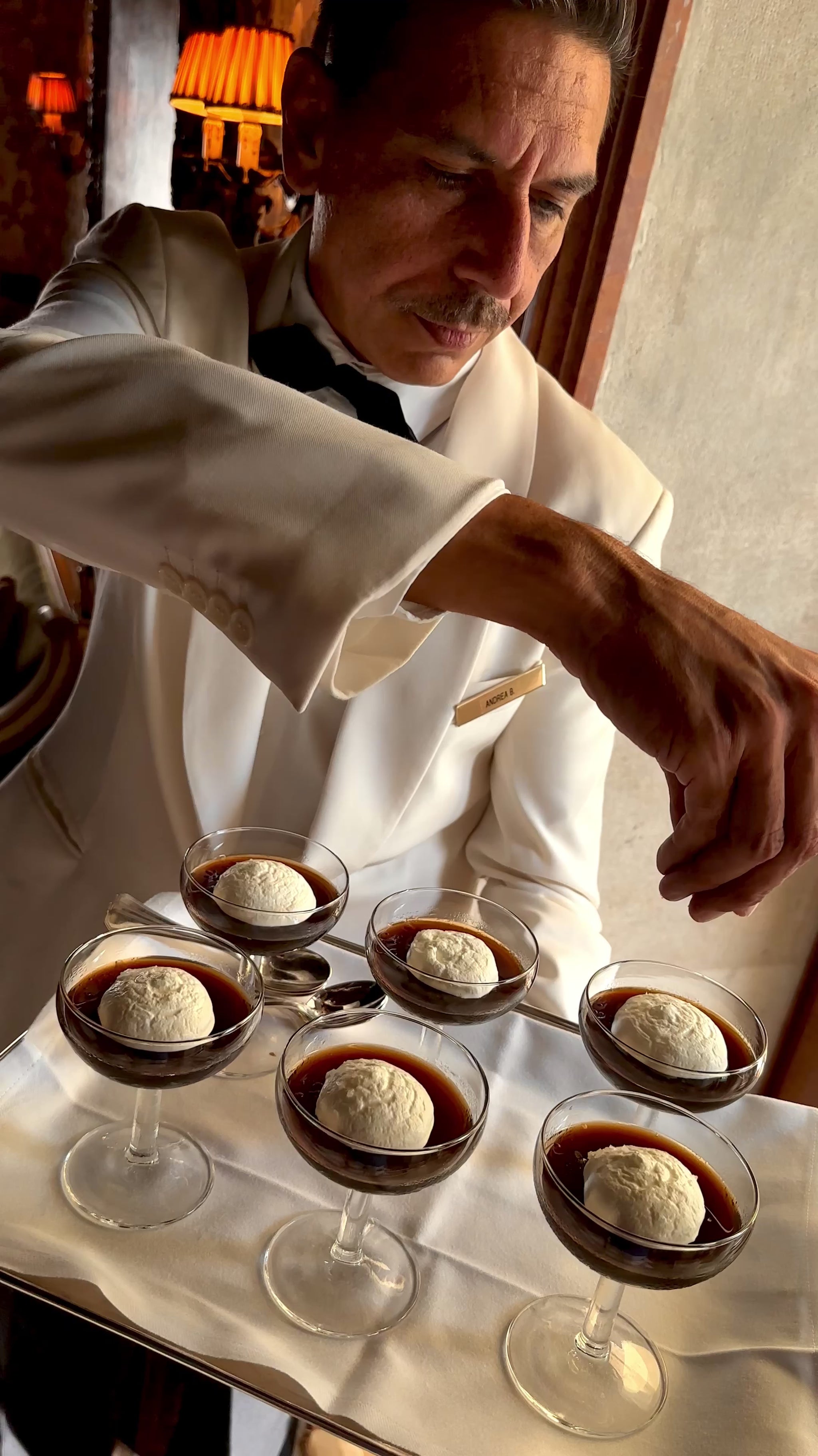 Video of server in white suit holidng tray of jelly cups in Italy